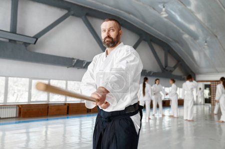 Téléchargez les photos : Maître Aikido sensei avec épée en bois à l'entraînement de groupe. Combat d'apprentissage avec boken de bambou - en image libre de droit