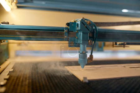 Téléchargez les photos : Machine laser CNC automatisée à gros plan fonctionnant avec une planche en bois. Procédé de menuiserie, découpe et gravure - en image libre de droit