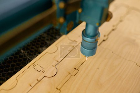 Téléchargez les photos : Machine laser CNC automatisée à gros plan fonctionnant avec une planche en bois. Procédé de menuiserie, découpe et gravure - en image libre de droit