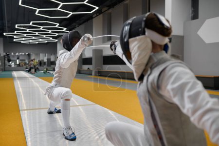Photo for Duel of fencers during fencing match. Training lesson of two swordsmen at martial art class concept. sparring partners fighting with rapiers - Royalty Free Image