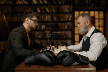 Photo for Senior versus young adult man chess battle with selective focus on boxer gloves. Business ideas, competition and strategy challenge concept - Royalty Free Image