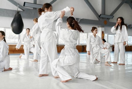 Photo for Teenage girls fighting at aikido training in martial arts school. Healthy lifestyle and sports concept - Royalty Free Image