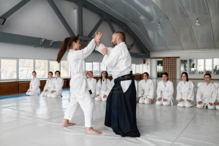 Foto de Sensei con joven hembra demostrando técnica aikido para otros estudiantes adolescentes. Entrenamiento en grupo en la escuela de artes marciales - Imagen libre de derechos