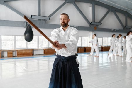 Foto de Retrato de maestro sensei aikido con espada de madera en el entrenamiento en grupo. Aprendiendo lucha con bambú boken - Imagen libre de derechos