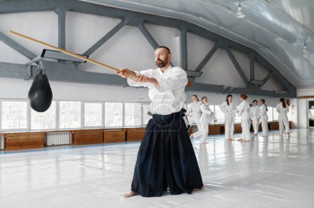 Téléchargez les photos : Maître Kendo pratiquant avec épée en bois pendant le temps de pause à l'entraînement. Concept d'apprentissage des arts martiaux - en image libre de droit