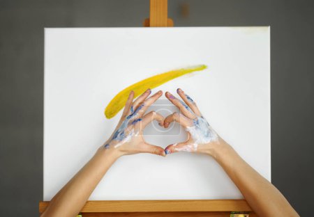 Téléchargez les photos : Composition des mains d'artiste faisant signe de forme de coeur sur toile d'image. Art thérapie avec amour, concept artistique et éducatif - en image libre de droit