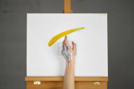 Photo for Female artist dirty hand over picture canvas making magic move to create beautiful picture drawaing with paints. Art class, therapeutic hobby and artistic education concept - Royalty Free Image