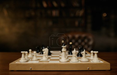 Téléchargez les photos : Chessboard avec des pièces blanches et noires sur table en bois avec fauteuil vintage de luxe. Concept de jeu tactique de stratégie - en image libre de droit
