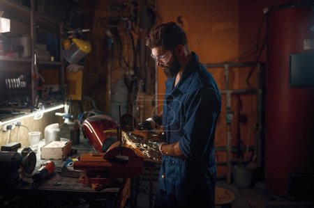 Photo for Repairman making and fitting spare part manually while working in workshop. Technician hand and sparks flying from machine - Royalty Free Image