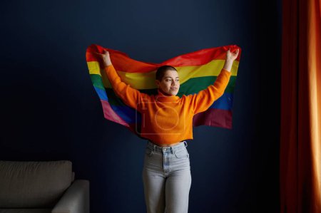 Foto de Retrato de una joven lesbiana sosteniendo la bandera del orgullo lgbtq actuando por la identidad sexual, la libertad y la igualdad - Imagen libre de derechos