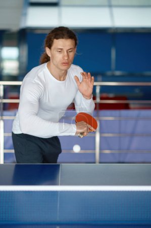 Foto de Retrato de atleta masculino feliz jugando al tenis de mesa en el club deportivo de entrenamiento. Milenial deportista profesional preparándose para el campeonato - Imagen libre de derechos