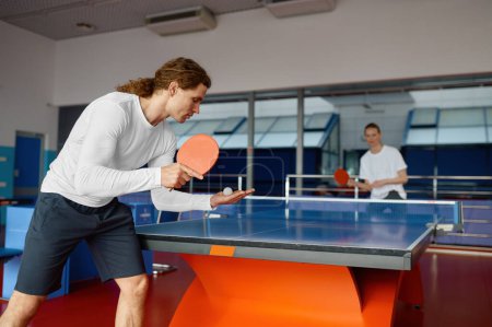 Photo for Man and woman playing table tennis, focus on sportsman player serving ball with racket. Sport and healthy lifestyle concept - Royalty Free Image