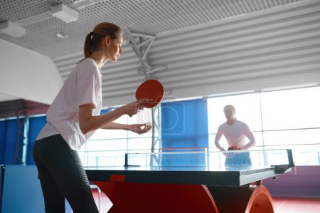 Foto de Vista recortada de la mujer jugando al ping pong de mesa con un amigo borroso en el club deportivo de juegos - Imagen libre de derechos