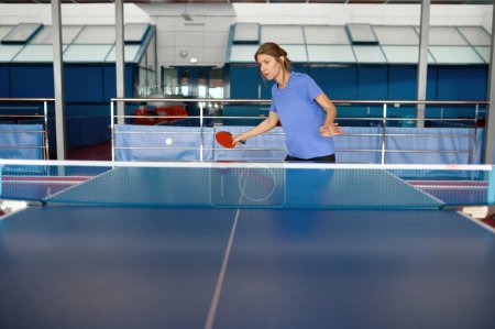 Photo for Beautiful adult woman dressed in sportswear playing table tennis in gym. Training class at ping pong gaming club - Royalty Free Image
