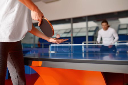 Jeune homme et jeune femme jouant au ping-pong, se concentrer sur le racket et le ballon à la main féminine. Couple loisirs actifs temps ensemble concept