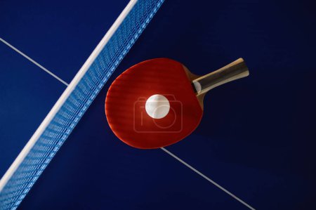Photo for Tennis racket and ball on ping-pong table with net prepared for game completion. Professional sport and hobby concept - Royalty Free Image