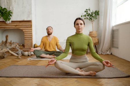 Photo for Young family couple practicing meditation sitting in lotus position. Morning yoga in pair, mindfulness exercise for wellness and relaxation - Royalty Free Image