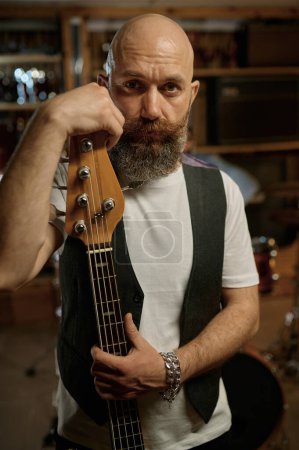 Téléchargez les photos : Portrait du guitariste du groupe rock avec son instrument de musique. barbu mature l'homme regardant caméra - en image libre de droit