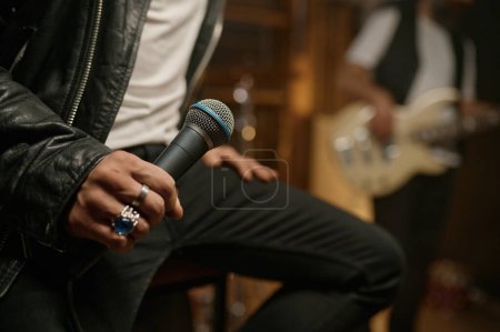 Photo for Closeup view of rock singer hand holding dynamic microphone. Music band performing in club concept - Royalty Free Image