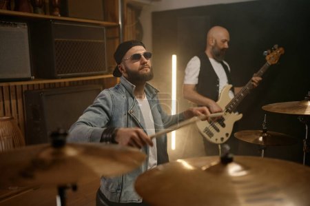 Photo for Rock band performance. Focus on stylish male drummer beating music rhythm on drum with sticks - Royalty Free Image