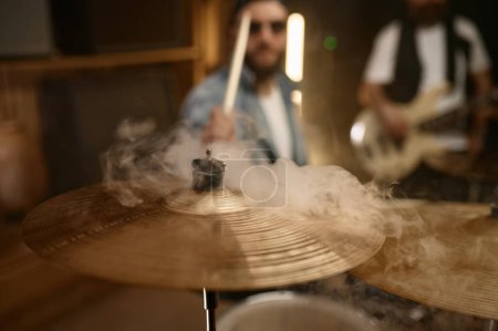 Téléchargez les photos : Plaque de tambour en cuivre en fumée, batteur jouant de la musique heavy metal rock battant un rythme fort - en image libre de droit