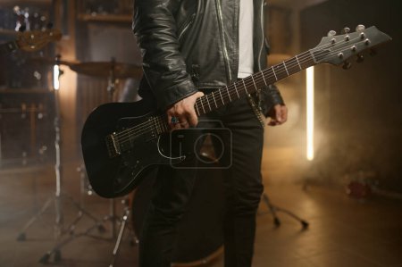 Guitariste du groupe de rock tenant un instrument de musique. Gros plan main masculine portant guitare sur fond de scène fumé