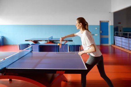Foto de Mujer joven pateando pelota jugando al tenis de mesa en el club deportivo. Mujer practicando ping pong antes del evento de competición - Imagen libre de derechos