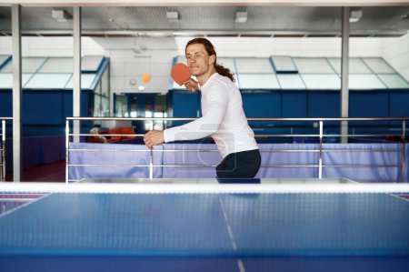 Téléchargez les photos : Portrait d'un jeune joueur de tennis de table s'entraînant dans un club sportif. Hipster gars appréciant ping-pong jeu pratiquant la technique - en image libre de droit