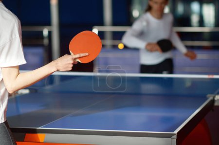 Foto de Enfoque selectivo en dos personas deportivas que juegan al tenis de mesa en interiores. Partido de ping pong amistoso masculino y femenino - Imagen libre de derechos