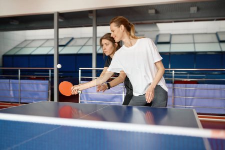Téléchargez les photos : Instructrice adulte enseignant le tennis de table aux étudiantes. Concept de vie sportive - en image libre de droit