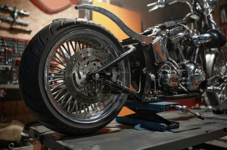 Photo for Closeup side view of custom motorcycle placed on lift platform at service station. Sport motorbike maintenance in garage - Royalty Free Image
