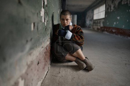 Foto de Mujer joven estresada mendigo sensación de miedo y miedo sentado en el suelo mirando a la cámara - Imagen libre de derechos