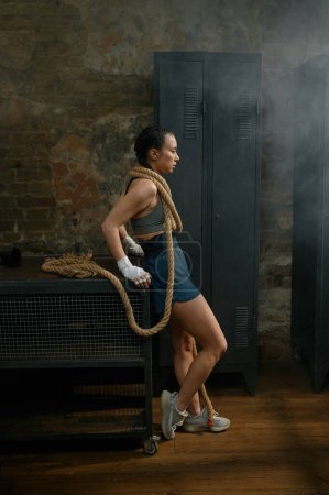 Téléchargez les photos : Mode boxer femme magnifique enveloppé dans la corde sur fond de gymnase loft. Concept de boxe - en image libre de droit