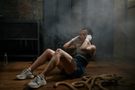 Foto de Mujer atractiva boxeadora haciendo ejercicios abdominales durante el entrenamiento en el gimnasio. Concepto deportivo de kickboxing profesional - Imagen libre de derechos