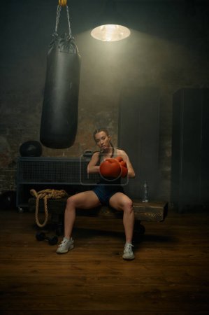 Photo for Portrait of professional beautiful sportive woman in red boxing gloves posing in gym studio - Royalty Free Image