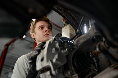 Foto de Mecánico automático profesional que trabaja en la vista del tren de aterrizaje del coche desde la parte interna del vehículo - Imagen libre de derechos