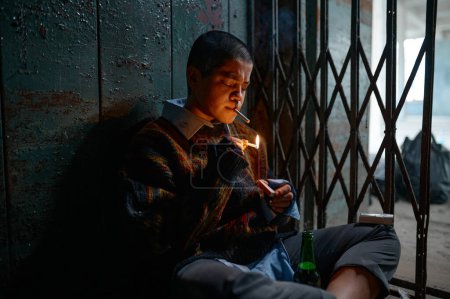 Foto de Mujer sin hogar fumador sosteniendo cigarrillo mirando partido ardiente en la mano. adicta adolescente mendigo y esperanza - Imagen libre de derechos