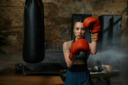 Foto de Boxeadora practicando puñetazos usando guantes de boxeo buscando concentrada y confiada - Imagen libre de derechos