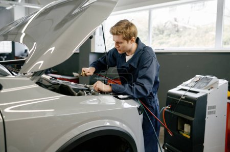 Photo for Male technician checking car air conditioning climate system. Professional diagnostics and refilling auto conditioner - Royalty Free Image