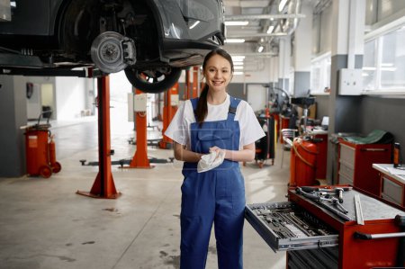 Photo for Portrait of beautiful smiling woman mechanic in overalls wiping hands with rag feeling satisfied with good work to fined, solve and troubleshooting car failure. Professional service - Royalty Free Image