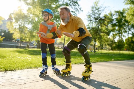 Photo for Little boy teaching his father riding roller skates in park. Son assisting daddy in rollerblading holding hand - Royalty Free Image