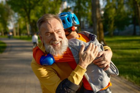 Foto de Retrato de un abuelo cariñoso abrazando a un nieto adorable. Familia feliz y patinaje sobre ruedas en el parque el fin de semana - Imagen libre de derechos
