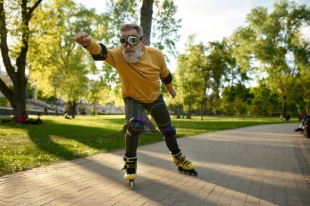 Téléchargez les photos : Homme mature drôle portant des lunettes de conduite rapide sur les patins à roulettes dans la rue de la ville - en image libre de droit