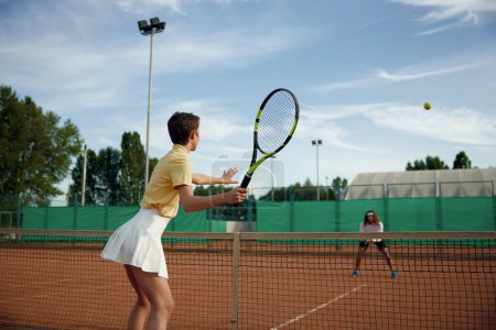 Foto de Un par de amigos deportivos jugando al tenis en la cancha afuera por la noche. Ocio recreativo hobby concepto de actividad - Imagen libre de derechos