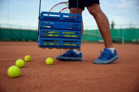 Téléchargez les photos : Vue rapprochée du joueur de tennis ramasser des balles dispersées sur le terrain après la formation de match. Profession professionnelle ou loisir concept de loisirs - en image libre de droit