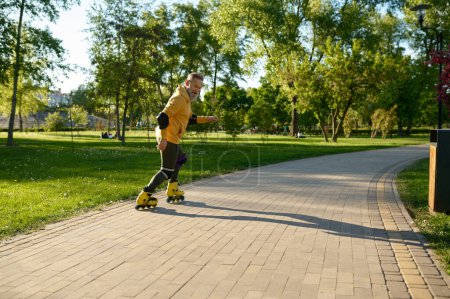 Foto de Hombre mayor moviéndose rápido en patines en el parque de la ciudad. Feliz jubilado aprender trucos de patinaje y acrobacias para montar en extrema - Imagen libre de derechos