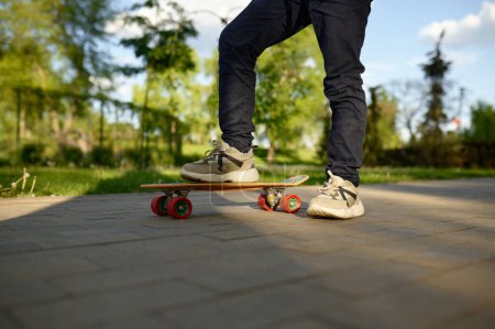 Foto de Pata de niño de primer plano con zapatillas en monopatín sobre fondo de calle. Tiempo de skate extremo el fin de semana - Imagen libre de derechos