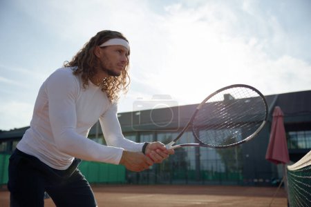 Foto de Jugador de tenis profesional sosteniendo raqueta de pie frente a la red. Actividad saludable y concepto de pasatiempo deportivo - Imagen libre de derechos