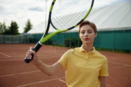 Téléchargez les photos : Portrait de jeune joueuse de tennis adolescente avec raquette sur fond de terrain de sport extérieur - en image libre de droit