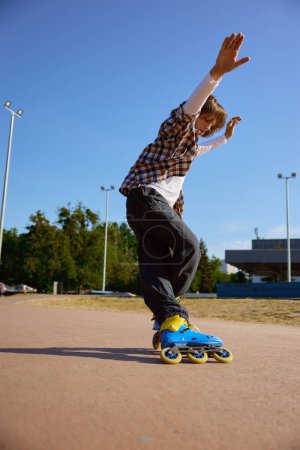 Photo for Active schoolboy rollerblading on street having training class for practicing free riding - Royalty Free Image